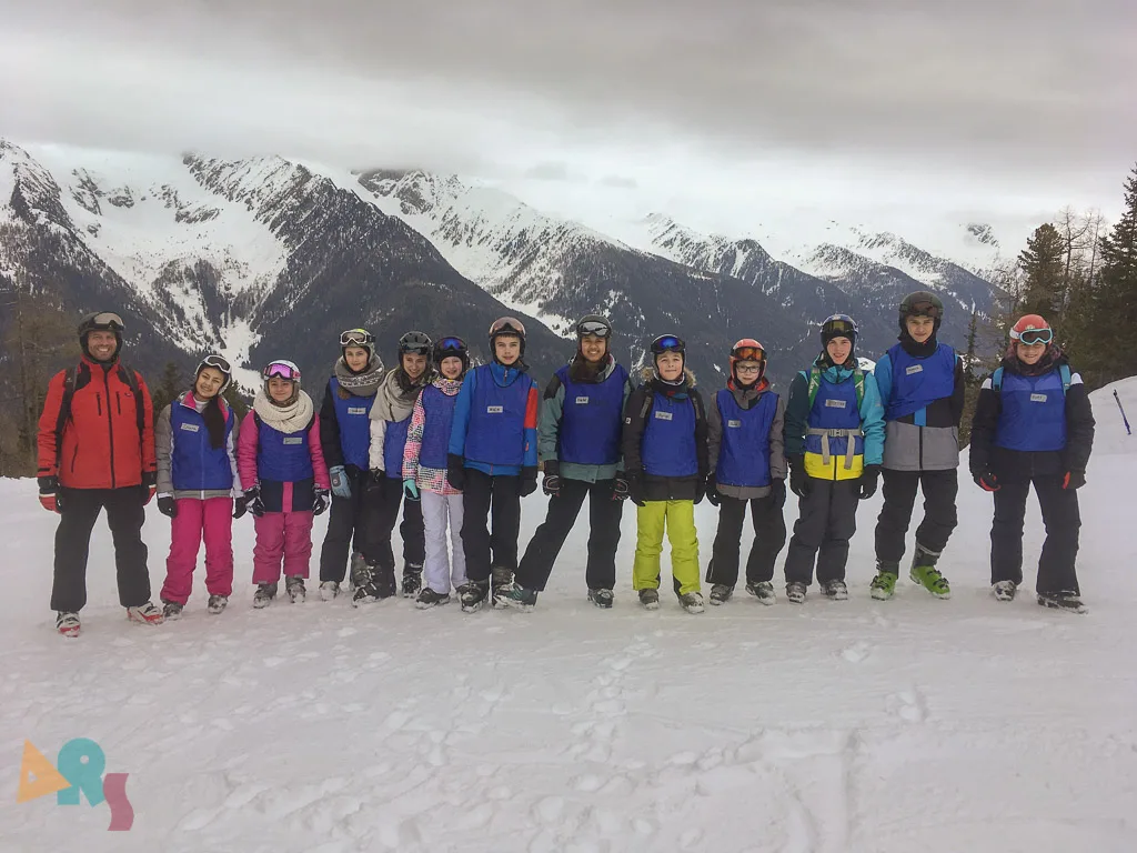 Skigruppe posiert vor der verschneiten Bergkette.